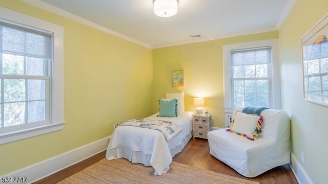 bedroom with ornamental molding, multiple windows, and hardwood / wood-style floors