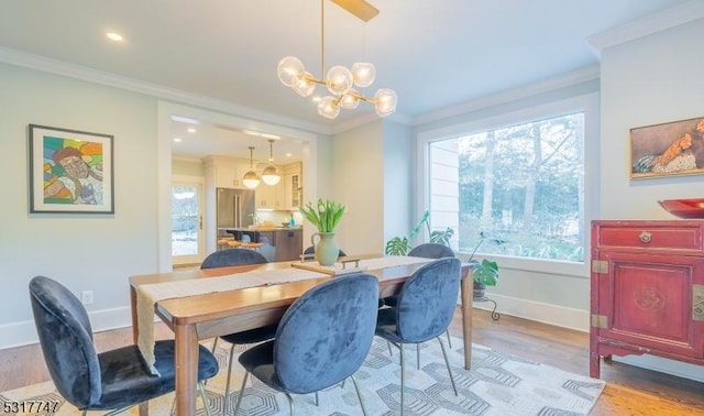 dining room with light wood-type flooring, plenty of natural light, crown molding, and a chandelier