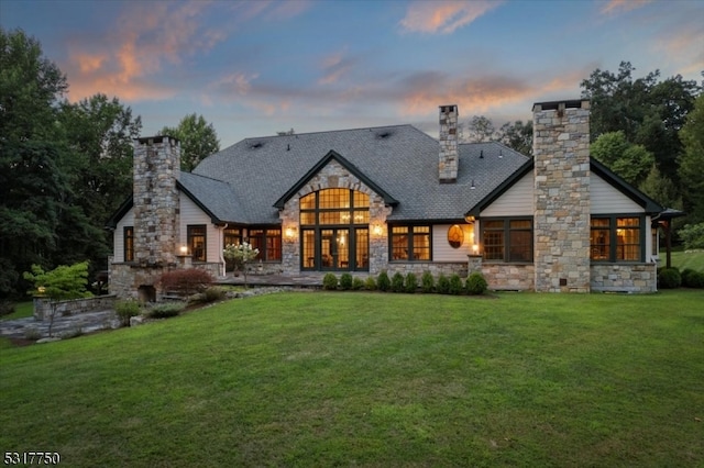 back house at dusk featuring a yard