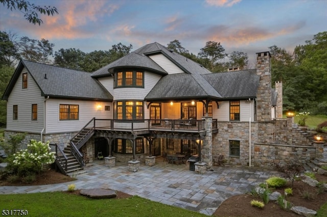 back house at dusk featuring a patio and a wooden deck