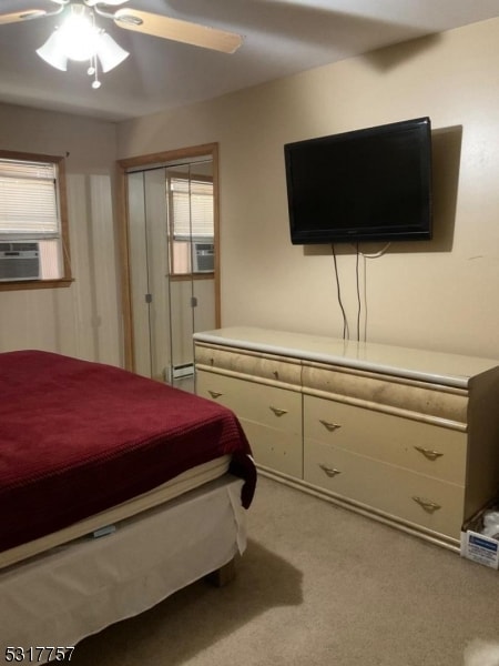 bedroom featuring a closet, light colored carpet, a baseboard radiator, and ceiling fan