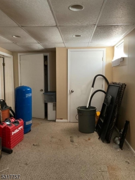 basement featuring a drop ceiling and carpet