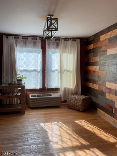 unfurnished room featuring hardwood / wood-style flooring and an AC wall unit