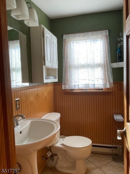 bathroom featuring a wealth of natural light, tile patterned floors, a baseboard heating unit, and toilet