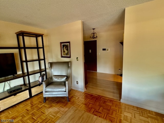 unfurnished room with a notable chandelier, a textured ceiling, and light parquet flooring