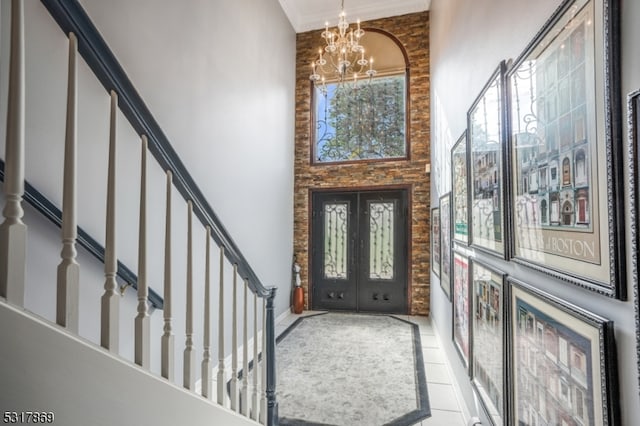 entrance foyer with tile patterned flooring, a chandelier, crown molding, a towering ceiling, and french doors