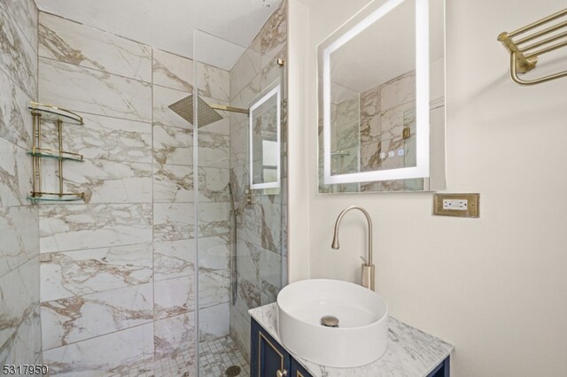 bathroom with a tile shower and vanity