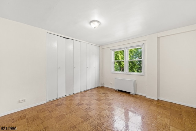 unfurnished bedroom with radiator and light parquet flooring