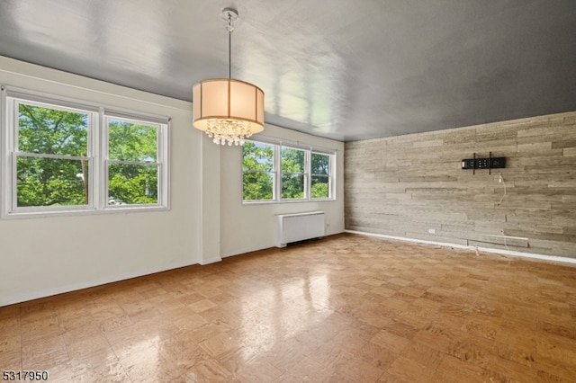 spare room with radiator heating unit and a wealth of natural light