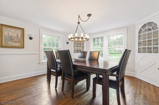 dining room with dark wood-type flooring, ornamental molding, and an inviting chandelier