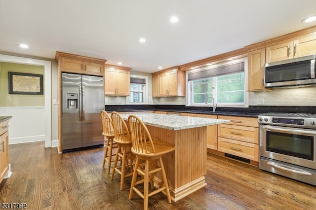 kitchen featuring a center island, dark hardwood / wood-style floors, stainless steel appliances, sink, and stone countertops