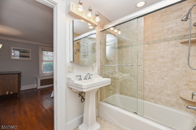 bathroom with ornamental molding, shower / bath combination with glass door, hardwood / wood-style flooring, and radiator