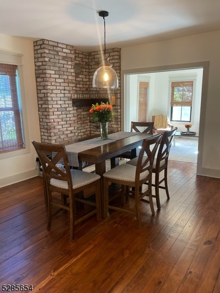 dining area featuring brick wall and dark hardwood / wood-style flooring