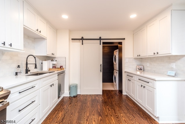 kitchen with stacked washer and clothes dryer, a barn door, white cabinetry, and dark hardwood / wood-style flooring