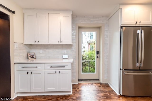 kitchen with a barn door, stainless steel refrigerator, dark hardwood / wood-style floors, and white cabinets