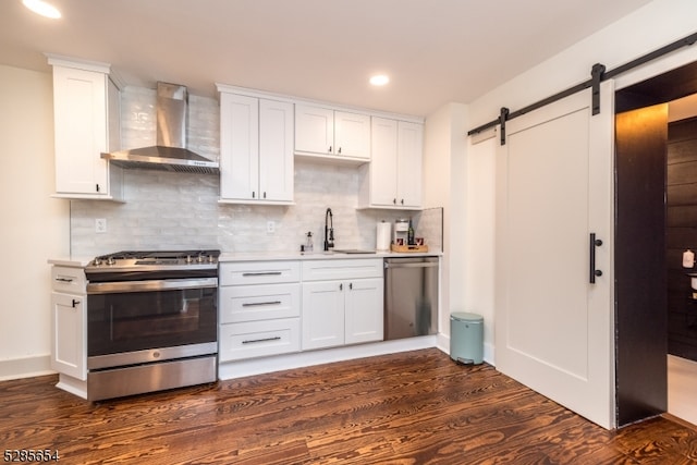 kitchen featuring wall chimney exhaust hood, sink, dark hardwood / wood-style floors, appliances with stainless steel finishes, and white cabinetry