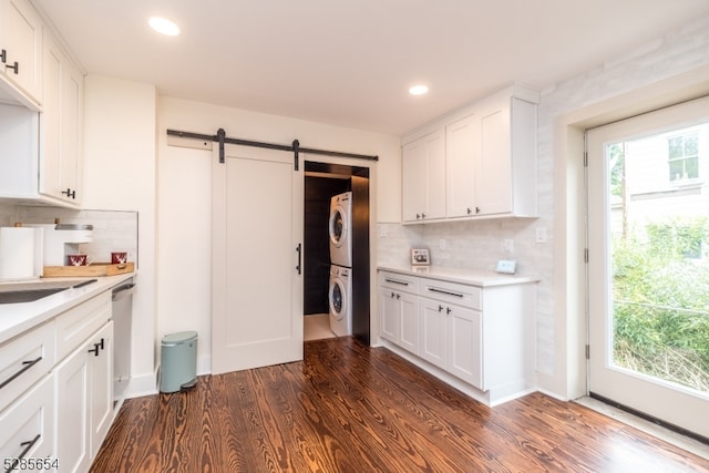 kitchen featuring stacked washer and clothes dryer, a barn door, white cabinetry, and dark hardwood / wood-style floors