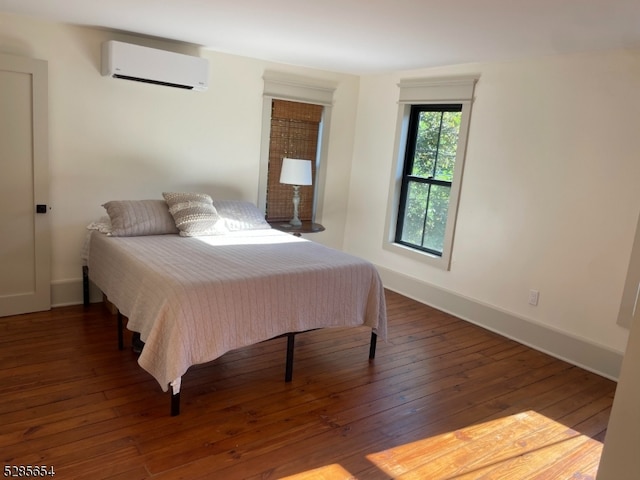 bedroom with dark wood-type flooring and a wall unit AC