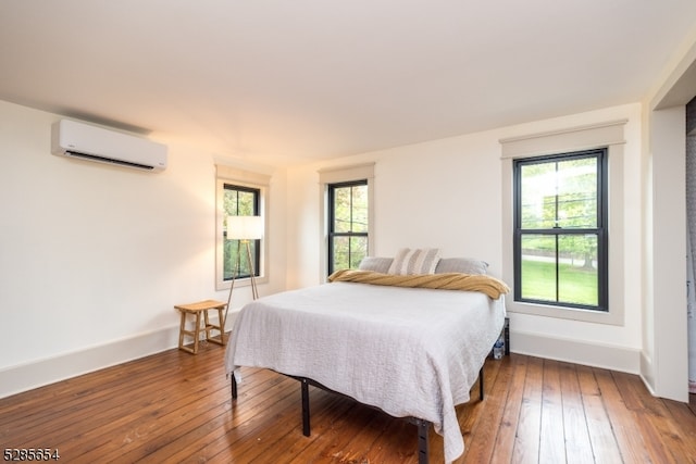 bedroom featuring wood-type flooring and a wall mounted AC