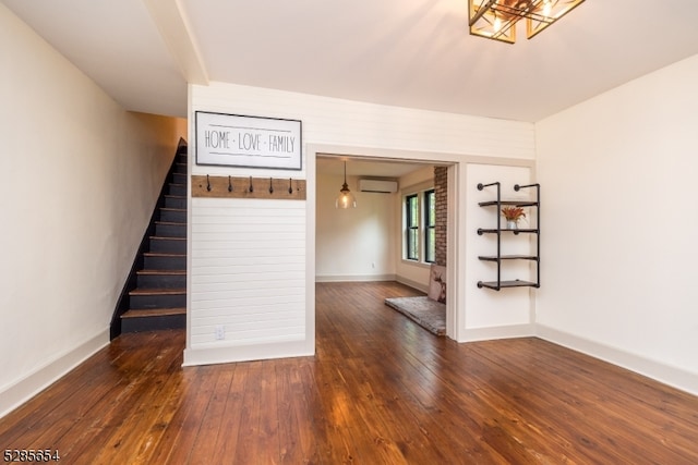 spare room featuring dark wood-type flooring and an AC wall unit