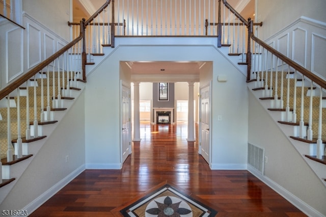 stairs featuring ornate columns, wood-type flooring, and ornamental molding