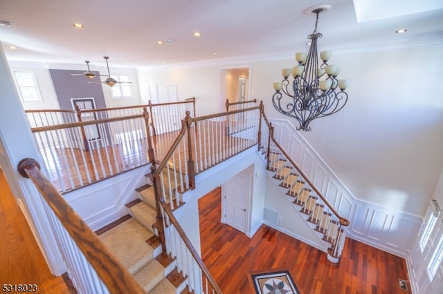 stairway featuring wood-type flooring, a skylight, an inviting chandelier, and ornamental molding