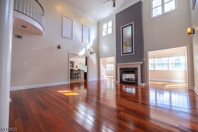 living room featuring wood-type flooring, ornamental molding, and a high ceiling