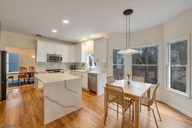 kitchen with visible vents, stainless steel appliances, white cabinets, tasteful backsplash, and a center island