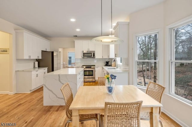 dining area with light wood-style flooring, recessed lighting, and baseboards