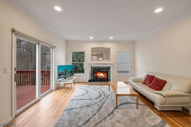 living room with light wood-style flooring, a high end fireplace, and ornamental molding