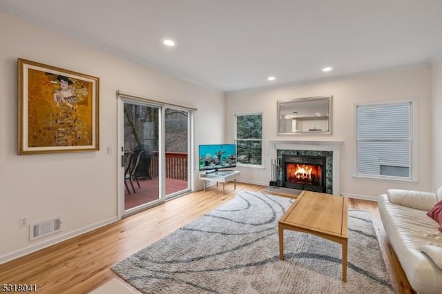 living area featuring wood finished floors, baseboards, visible vents, a premium fireplace, and recessed lighting