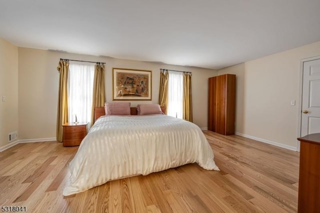 bedroom featuring multiple windows, baseboards, visible vents, and light wood finished floors