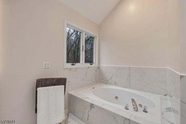 bathroom with vaulted ceiling, marble finish floor, and a whirlpool tub