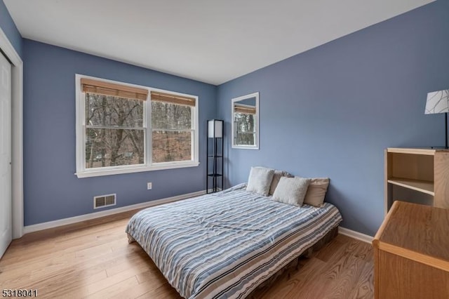 bedroom with visible vents, baseboards, and wood finished floors