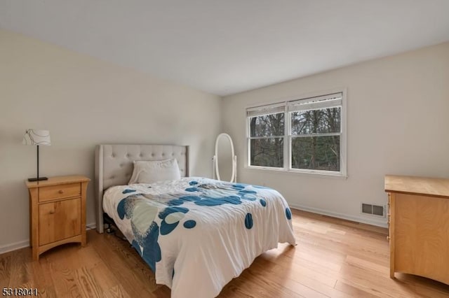 bedroom featuring light wood finished floors, visible vents, and baseboards