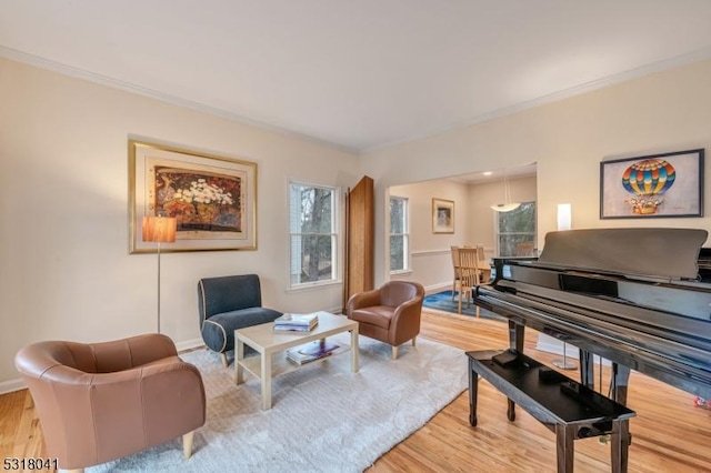 living area with baseboards, light wood-style floors, and crown molding