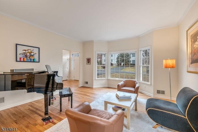 living room with visible vents, baseboards, wood finished floors, and crown molding