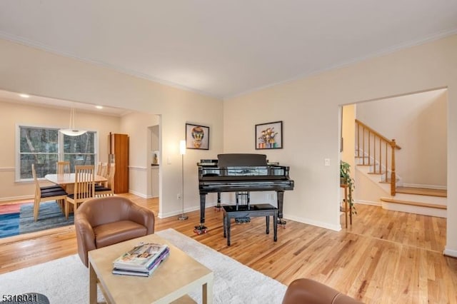 living room featuring stairs, crown molding, wood finished floors, and baseboards