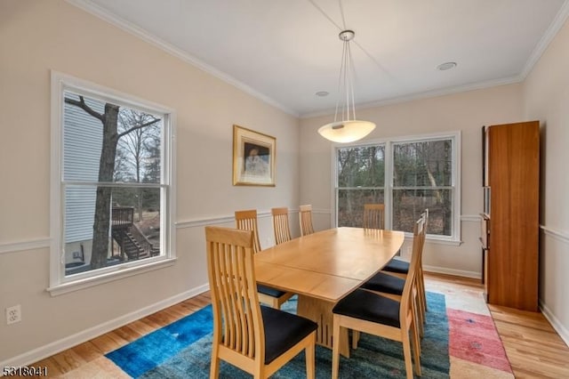 dining area with crown molding, baseboards, and light wood finished floors