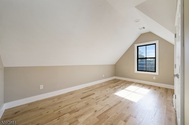 additional living space with light wood-type flooring and vaulted ceiling