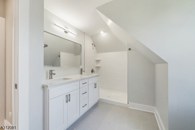 bathroom featuring tile patterned floors, a shower, vanity, and lofted ceiling