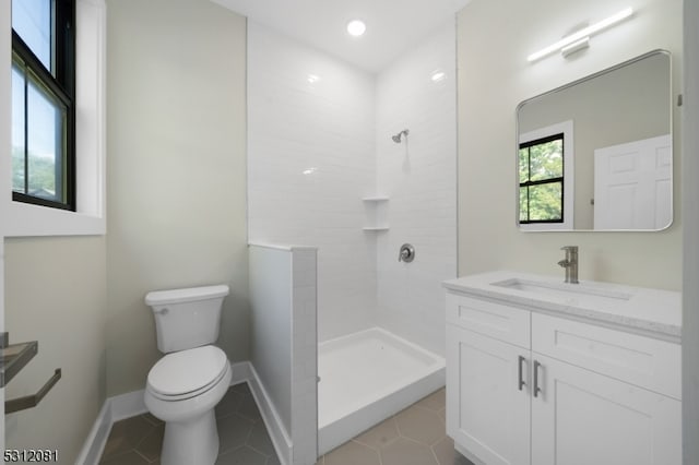 bathroom featuring tile patterned flooring, toilet, a tile shower, and vanity