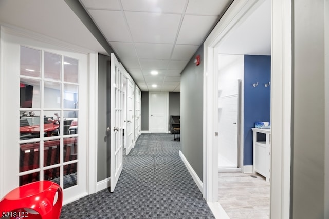 corridor with a paneled ceiling and carpet flooring