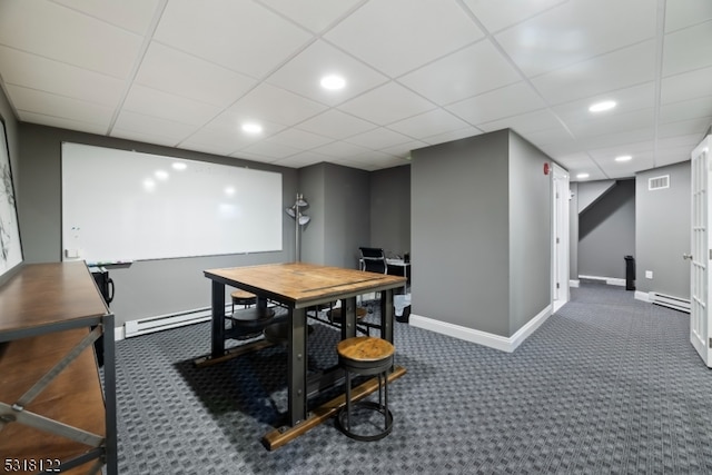 home office with a paneled ceiling, baseboard heating, and dark colored carpet