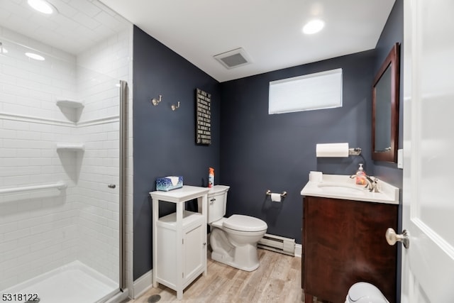 bathroom with vanity, hardwood / wood-style floors, a baseboard heating unit, a shower with shower door, and toilet