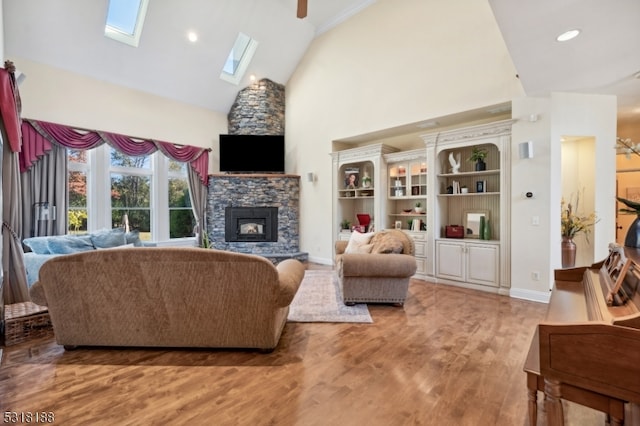 living room featuring hardwood / wood-style floors, a skylight, a fireplace, high vaulted ceiling, and ceiling fan