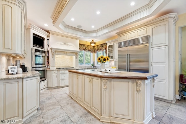 kitchen with decorative backsplash, cream cabinets, ornamental molding, a center island, and appliances with stainless steel finishes