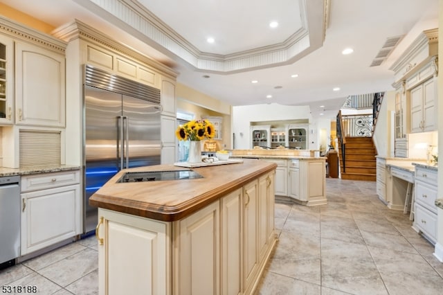 kitchen with cream cabinets, appliances with stainless steel finishes, crown molding, wooden counters, and a center island