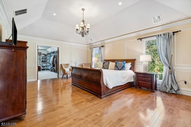 bedroom with a walk in closet, a closet, lofted ceiling, light hardwood / wood-style flooring, and a chandelier