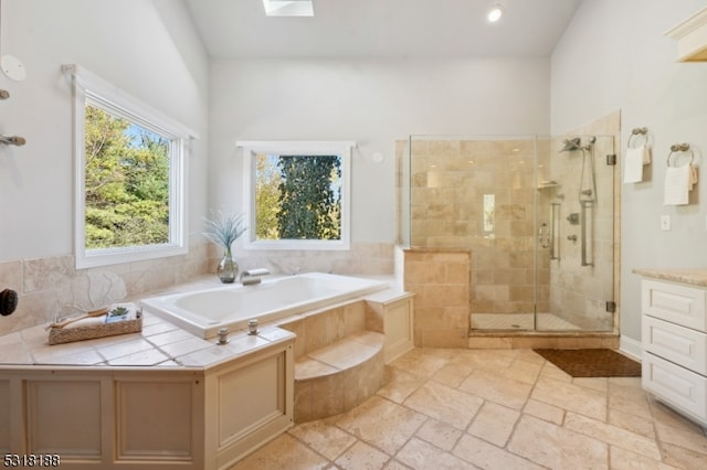 bathroom with vanity, shower with separate bathtub, a skylight, and a wealth of natural light